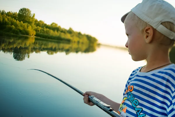 Bambino con un berretto pesca un attrezzo da pesca nel fiume in estate — Foto Stock