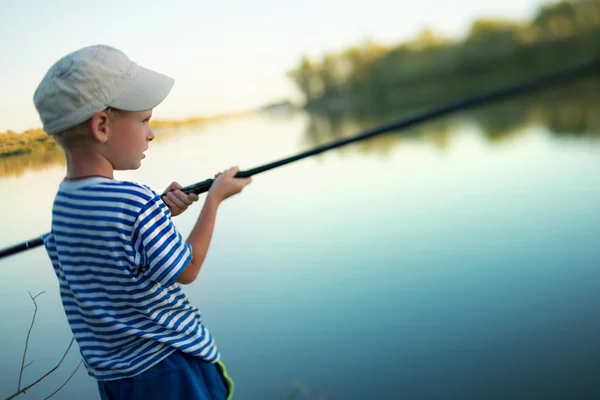 Niño en una gorra pesca un aparejo de pesca en el río en verano — Foto de Stock