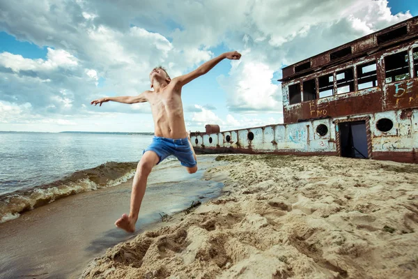 Shorts menino é saltos felizes e vira na praia no verão — Fotografia de Stock