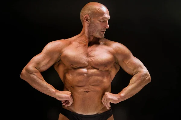Bald male athlete bodybuilder on a dark background — Stock Photo, Image