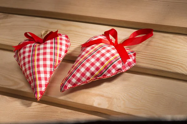 Deux cœurs cousus de tissu à carreaux rouges sur la planche, un symbole d'amour — Photo