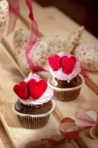 Cupcakes with cream and red hearts on a wooden table — Stock Photo, Image