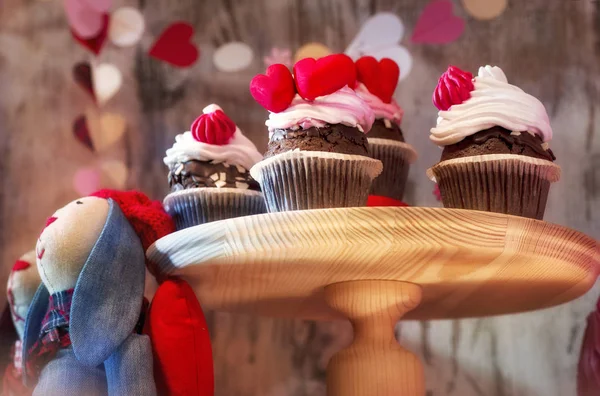 Кексы со сливками на стойке рядом с мягкими игрушечными кроликами. Романтические отношения . — стоковое фото