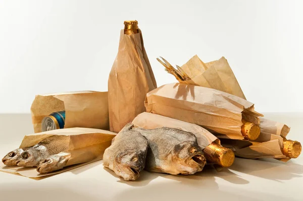 Gedroogde vis en bierflesjes verpakt in bruine papieren zakken — Stockfoto