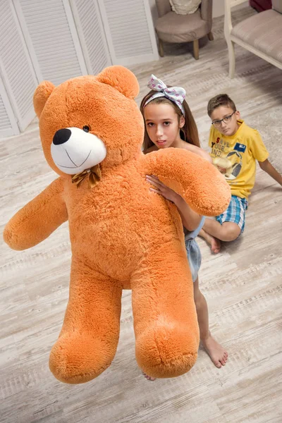 Boy and girl teenagers at home playing with orange teddy bear — Stock Photo, Image