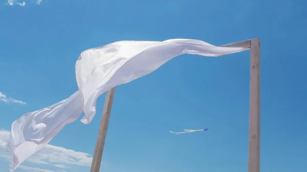 wind blows white curtains on a canopy on the beach