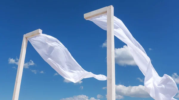 wind blows white curtains on a canopy on the beach