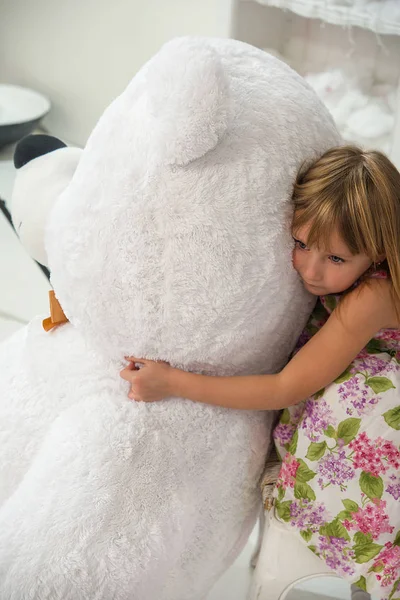 Menina abraça um brinquedo de um grande urso polar — Fotografia de Stock