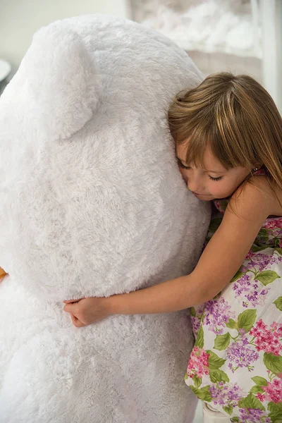 Menina abraça um brinquedo de um grande urso polar — Fotografia de Stock