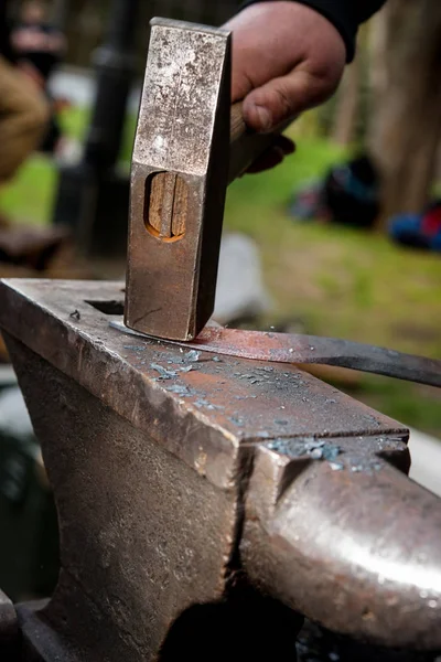 Мастер человек кует меч из раскаленного металла на наковальне — стоковое фото