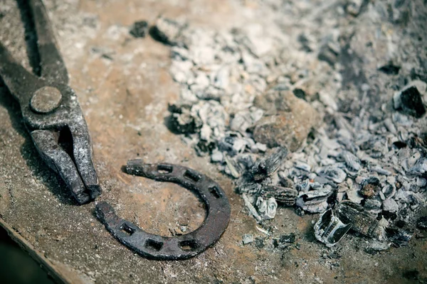 In the ashes from the blacksmith's forge lie the tongs and horseshoe for the horse — Stock Photo, Image