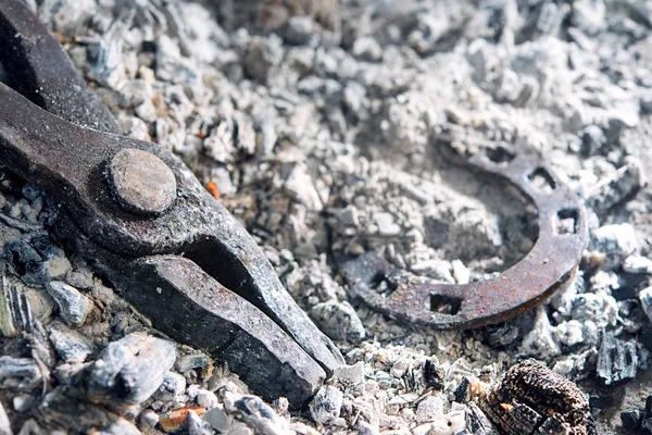 In the ashes from the blacksmith's forge lie the tongs and horseshoe for the horse — Stock Photo, Image
