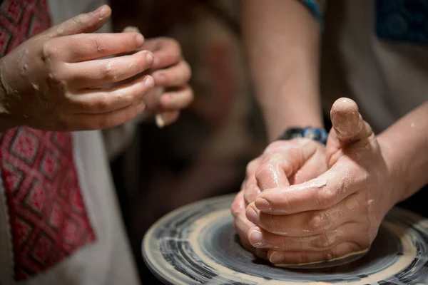 Вчитель навчає дитину, як зробити керамічну тарілку на купі гончаря. Крупним планом руки дитини і господарів . — стокове фото
