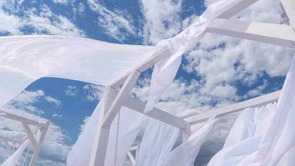 Sheds  awning with fabric white curtains on the seashore breeze in the wind