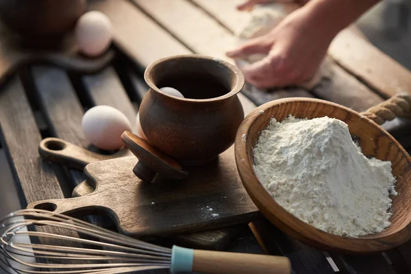 Ingrédients pour la pâte sur la table - farine, œufs. Femme pétrit la pâte avec ses mains . — Photo