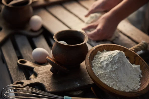 Ingrédients pour la pâte sur la table - farine, œufs. Femme pétrit la pâte avec ses mains . — Photo