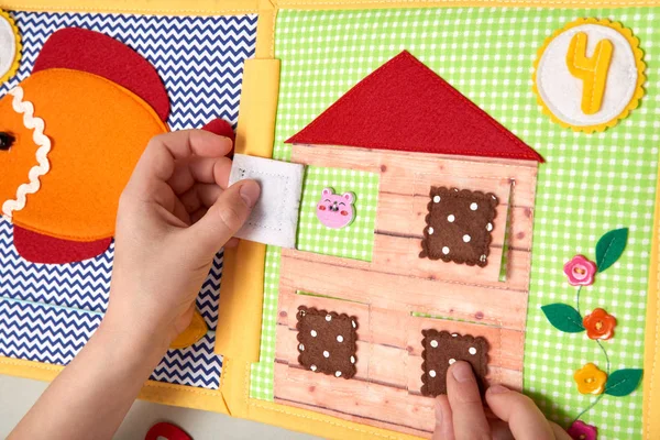 CHILDREN'S TEXTILE TRAINING BOOK. TOY HOUSE FROM FELT, CHILD PLAYING HANDS — Stock Photo, Image