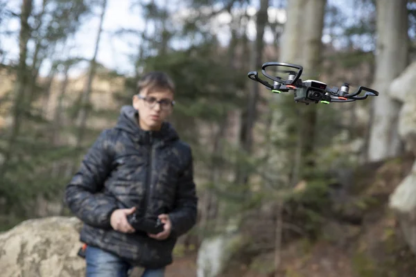 Teen boy controls a drone on a remote control drone in a park — Stock Photo, Image