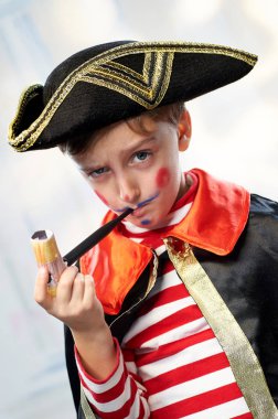 Little boy in a pirate sailor costume smokes a toy pipe. clipart
