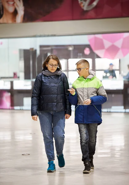 Mamá y su hijo en chaquetas están hablando en el centro comercial . — Foto de Stock