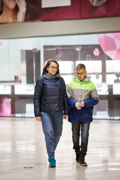 Mamá y su hijo en chaquetas están hablando en el centro comercial . — Foto de Stock