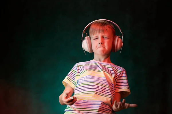 Little boy listens to his favorite music in modern wireless headphones, in the studio — Stock Photo, Image