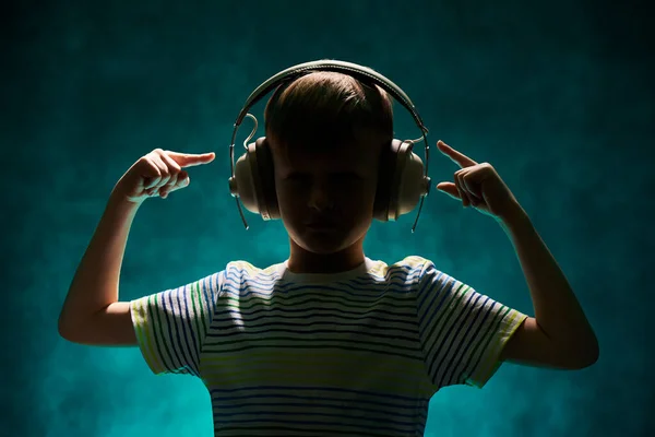 Silhouette of a little boy listens to his favorite music in modern wireless headphones in the studio — 스톡 사진