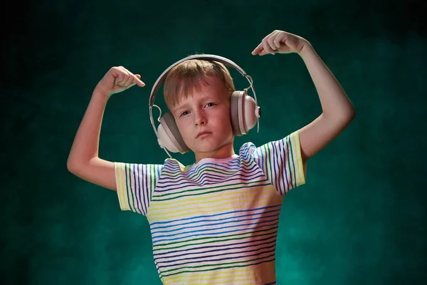Kleine jongen luistert naar zijn favoriete muziek in moderne draadloze hoofdtelefoon, in de studio — Stockfoto