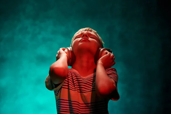 Kleiner Junge hört seine Lieblingsmusik in modernen drahtlosen Kopfhörern im Studio — Stockfoto
