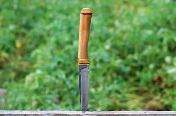 Hunting knife with a dark blade stuck in a board — Stock Photo, Image