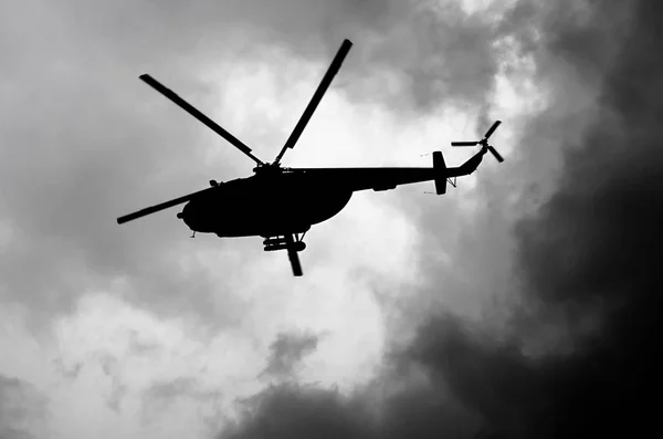 Silhouette of a helicopter in the clouds, black and white — Stock Photo, Image