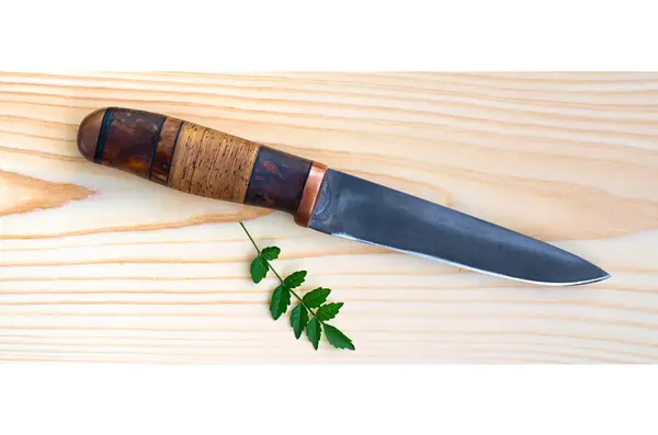 Lovecký nůž s listy na dřevěný povrch — Stock fotografie