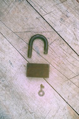 Açık asma kilit ve anahtar üstünde ahşap arka plan, retro tonlama