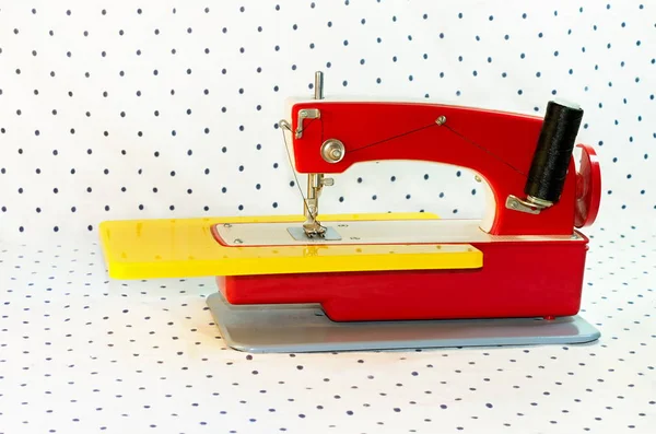 Máquina de coser, juguete infantil de color rojo sobre un fondo blanco con puntos — Foto de Stock