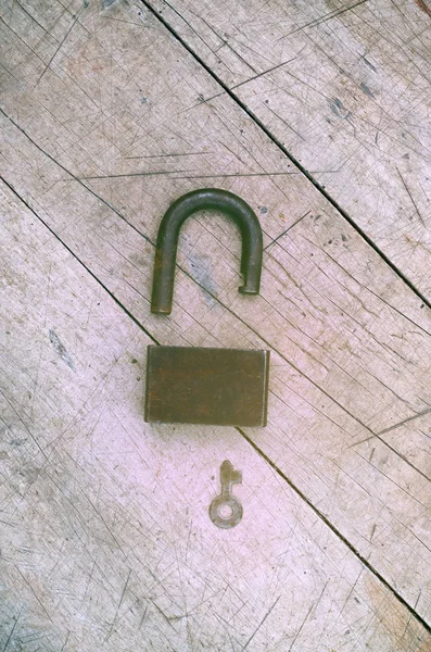 Açık asma kilit ve anahtar üstünde ahşap arka plan, retro tonlama