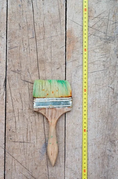 Pincel en pintura verde y cinta métrica sobre un fondo de madera — Foto de Stock