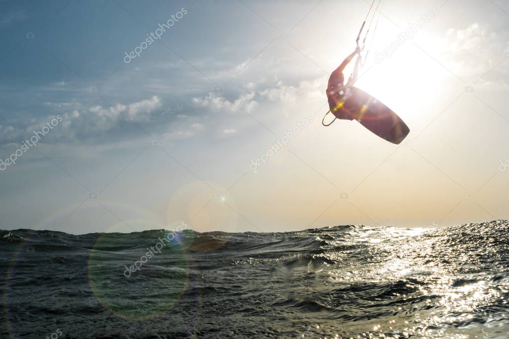 Surfer jumping at sunset over the golden sea