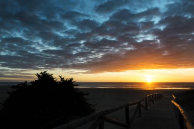 Günbatımı bulutlar ile mavi gökyüzü altında kumsalda