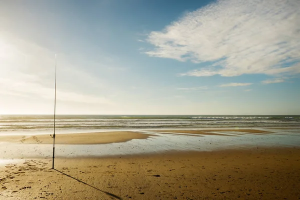 angling with a fishing rod on a deserted beach