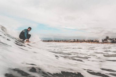 Sahile yakın bir dalga yakalamak sörfçü