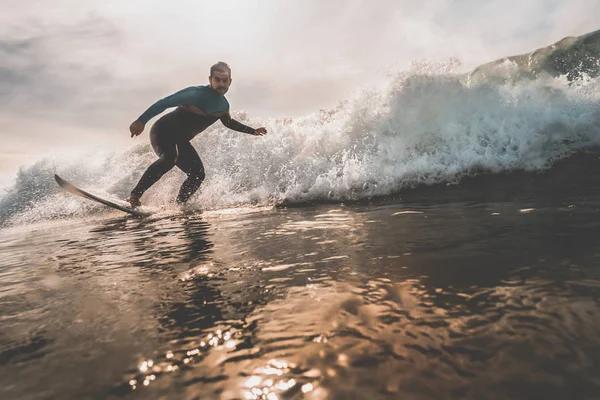 Ung man surfa en våg vid solnedgången — Stockfoto