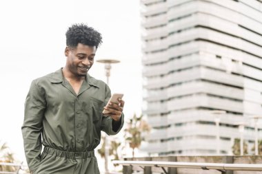 Siyah adam gülümsüyor ve telefonda mesaj yolluyor.