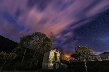 Yıldızlı gece gökyüzü küçük bir barakanın üzerindeki bulutlarla