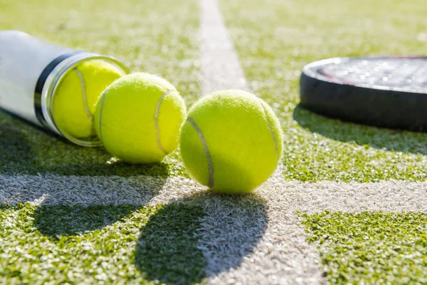 paddle tennis racket and tube with balls on turf