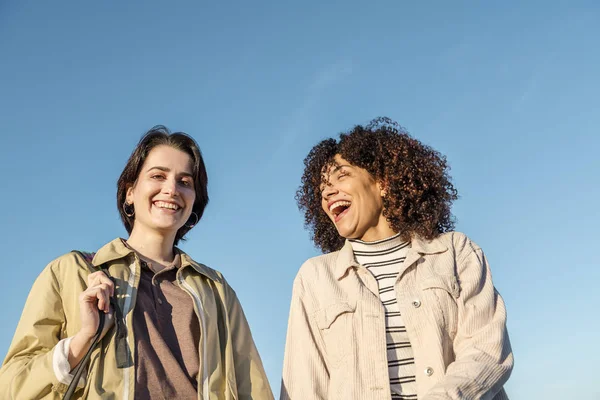 Two young women laughing with blue sky background — 图库照片