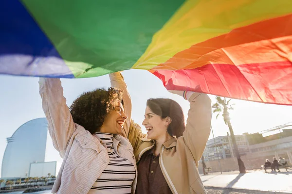Дві геї сміються з веселковим прапором — стокове фото