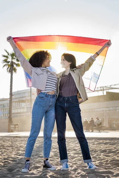 Дві гей дівчата махають веселкою прапор — стокове фото
