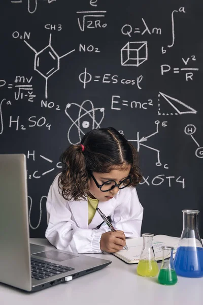Mała Naukowiec Dziewczyna Okularami Studiuje Komputerem Robi Notatki Tle Tablicy — Zdjęcie stockowe