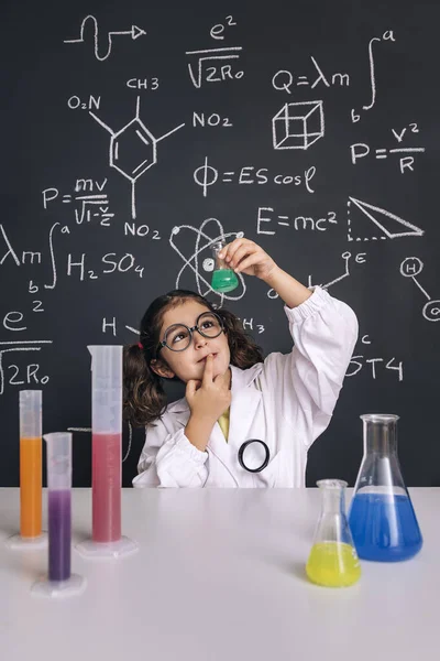 Dziecko Naukowiec Okularach Płaszczu Laboratoryjnym Szuka Kolby Płynem Chemicznym Tle — Zdjęcie stockowe