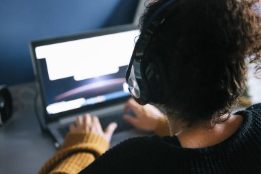 Kulaklıklı, evde dizüstü bilgisayarda çalışan girişimci bir kadının arka planı, teknoloji ve tele çalışma konsepti, seçici odaklanma